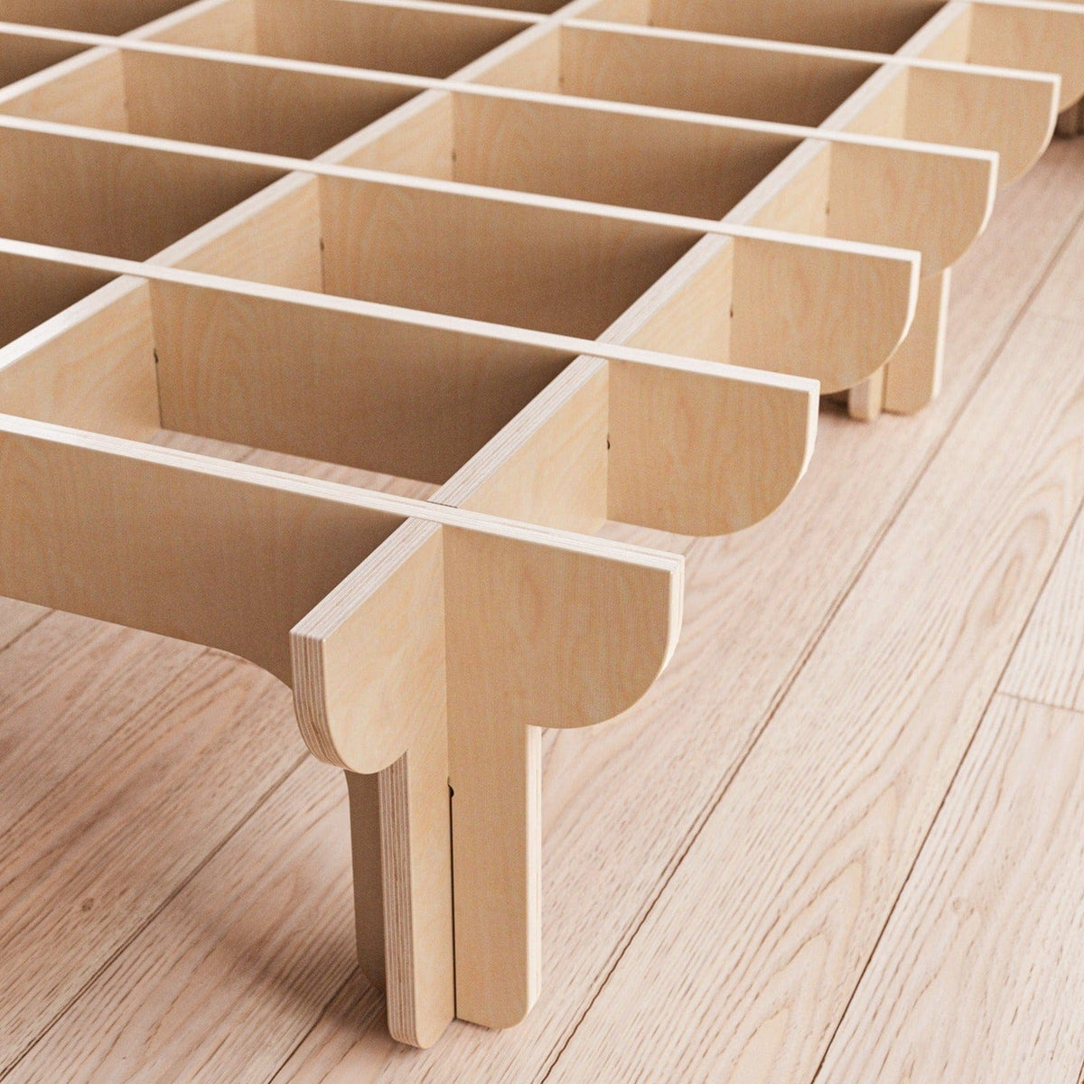 Close-up of the DOVID bed frameโs unfinished natural wood support system, showing interlocking slats, rounded joints and multiple legs