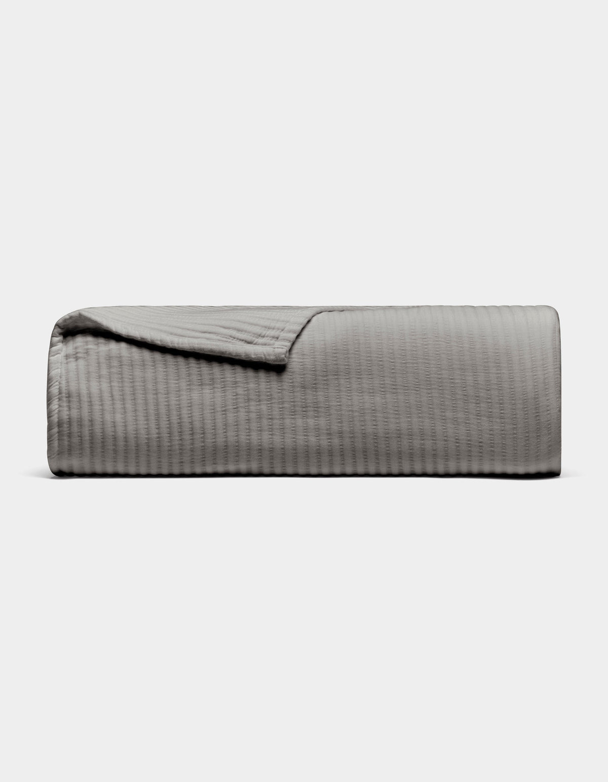 Gray Bamboo Coverlet folded on a pale background, with one corner turned back to show its narrow ribbed texture and finished edge.