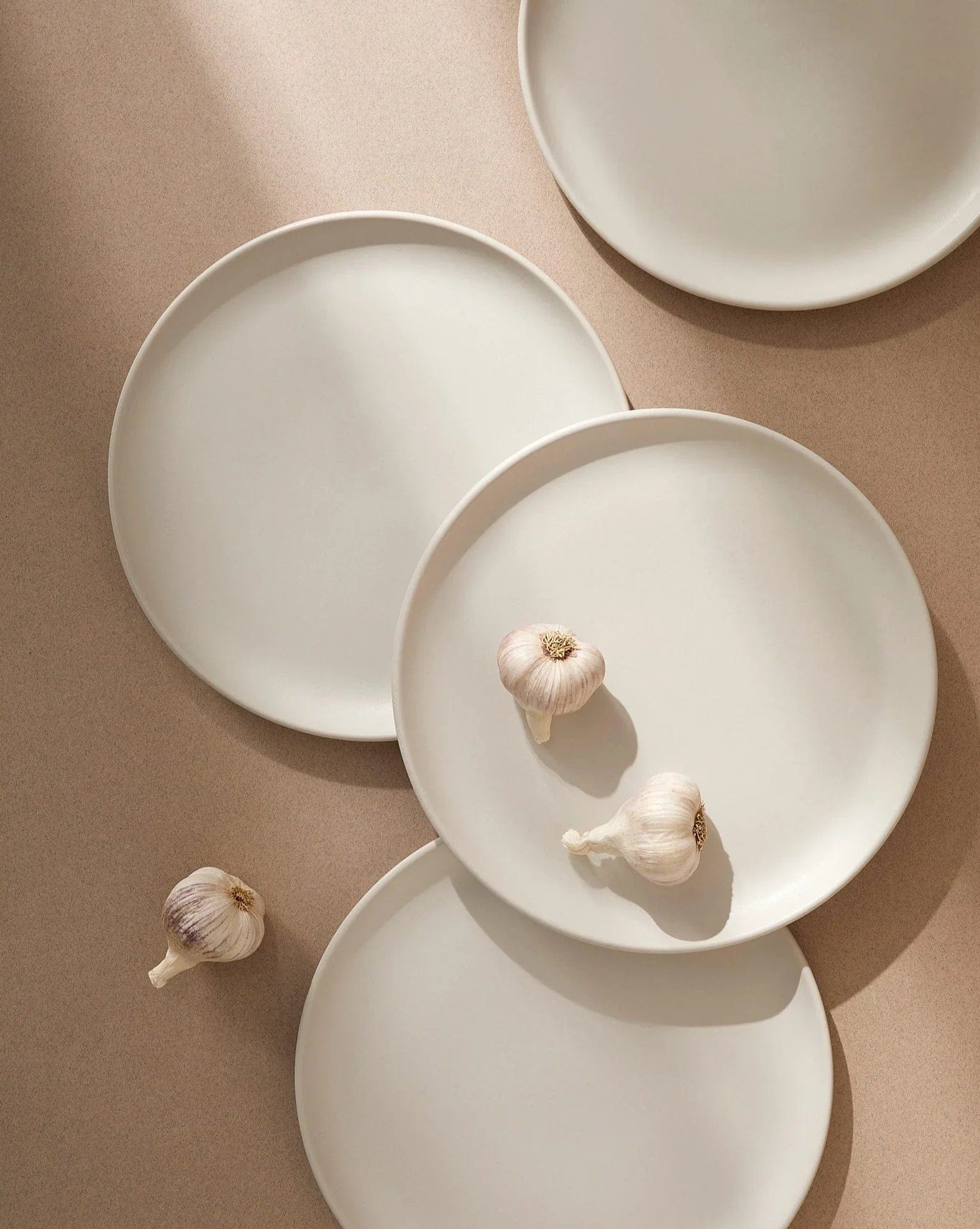 Stoneware dinner plates in Matte White overhead view with garlic