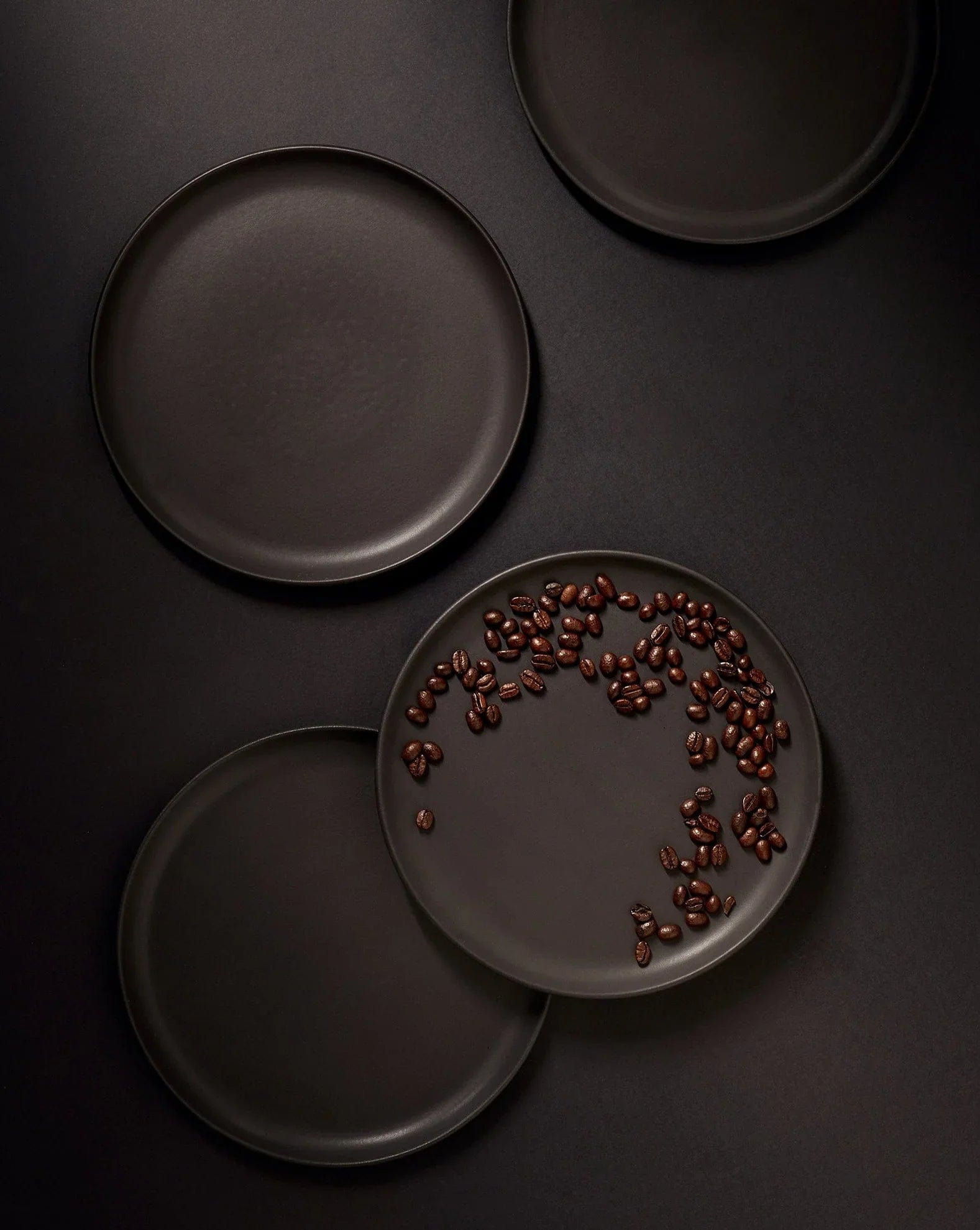 Stoneware dinner plates in Matte Black overhead view with peppercorns
