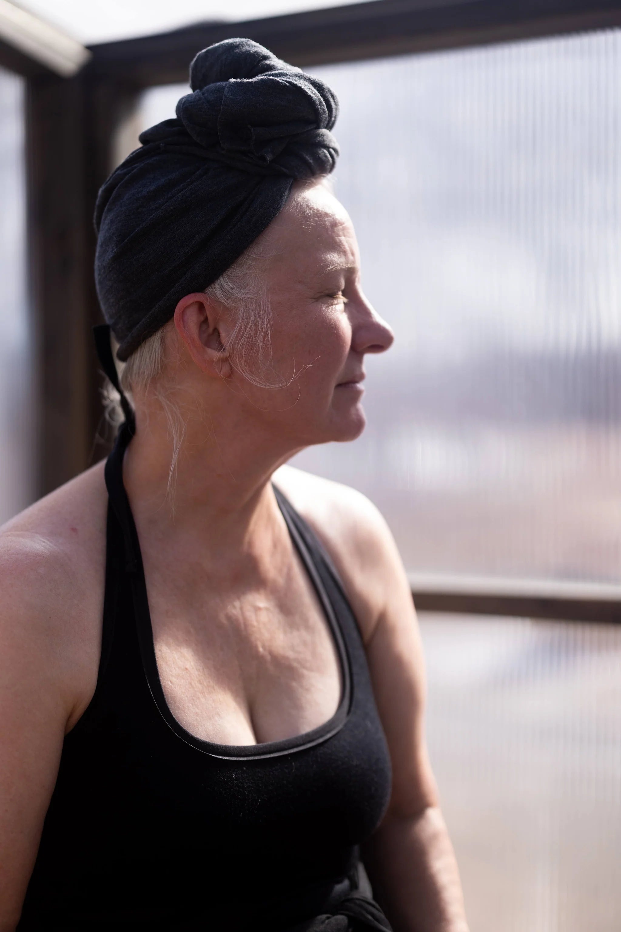 Woman wearing a charcoal merino wool sauna bath suit after a sauna session, showcasing natural breathability and comfort.