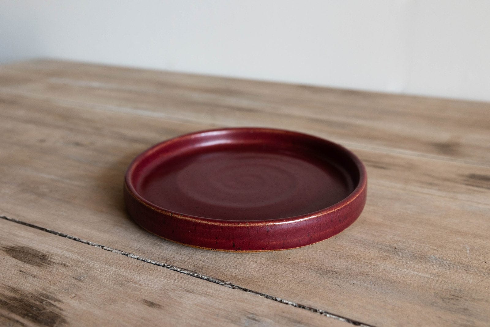 Burgundy handmade small earthenware salad plate on wood table