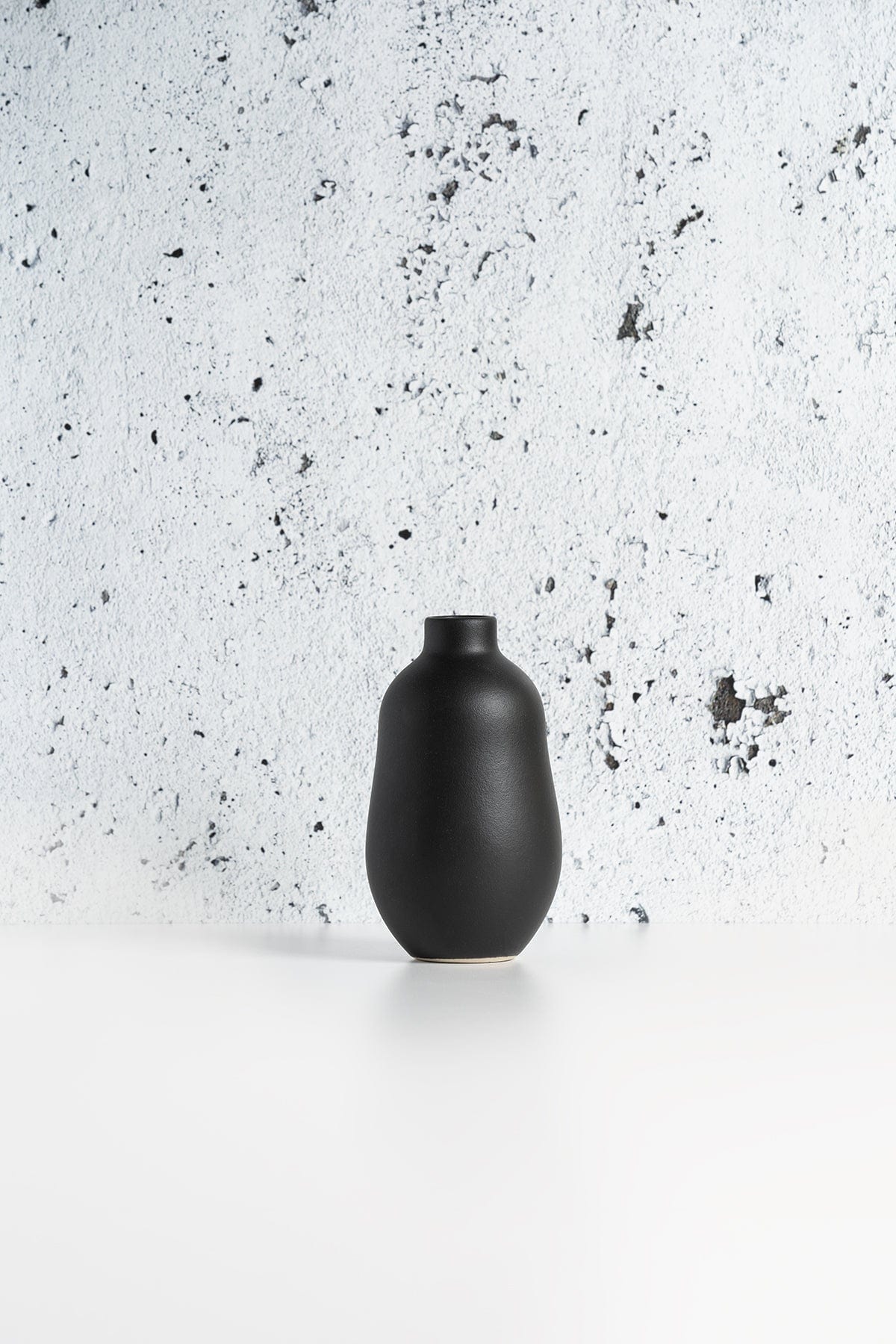 Stoneware vase in Matte Black against textured concrete background