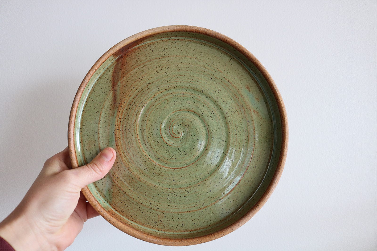Handmade ceramic small plate with spiral texture, held in hand, by KJ Pottery