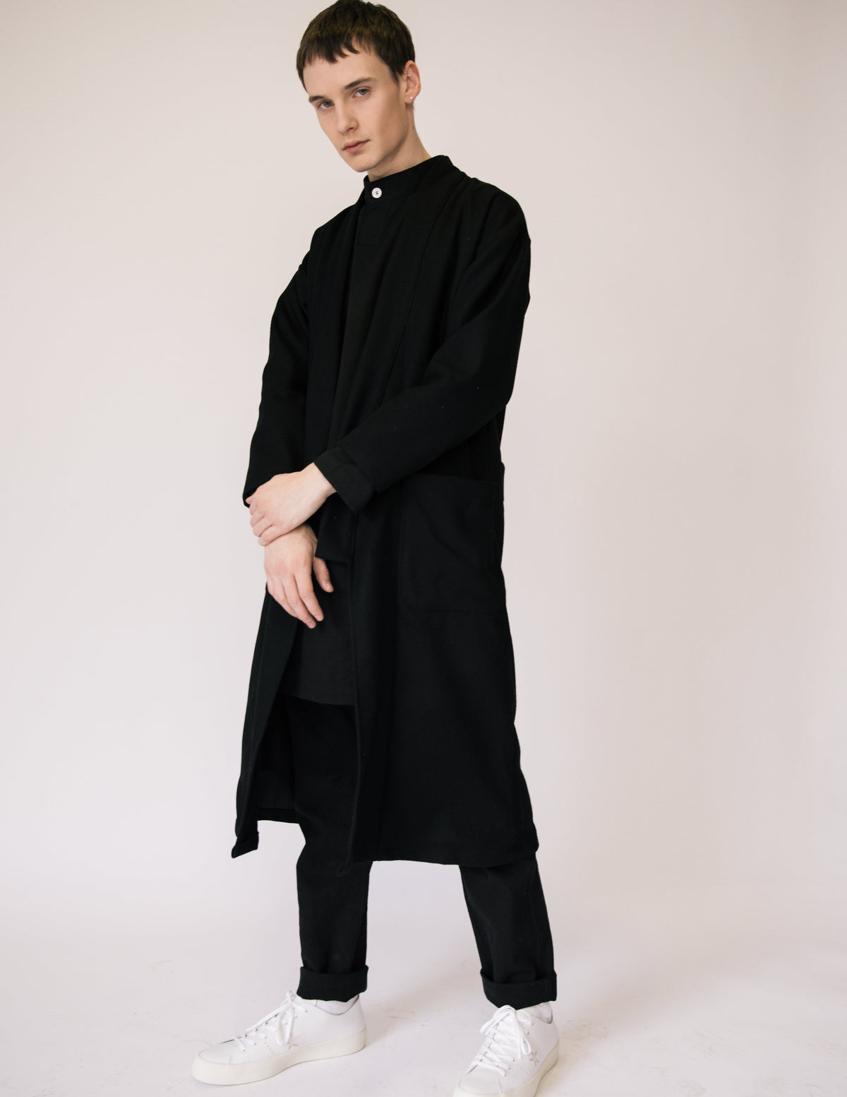 Model wearing the long black wool kimono over a black outfit with white sneakers.