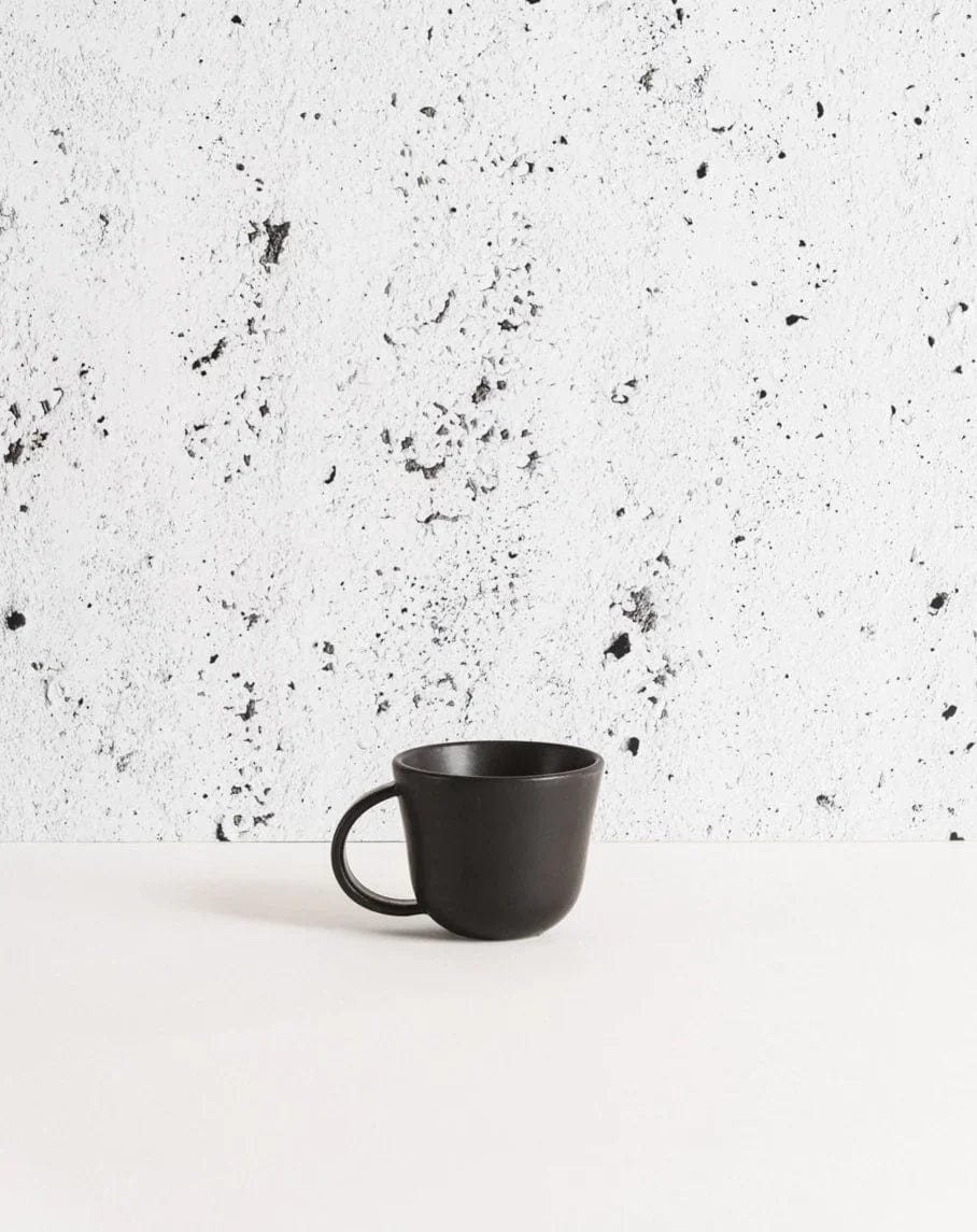 Stoneware mug in Matte Black against textured concrete background