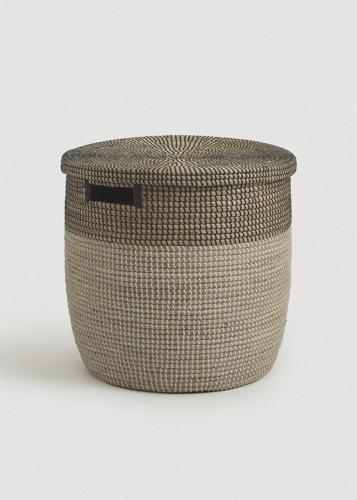 Large two-tone seagrass storage basket with a natural body, black upper band, flat lid, and rectangular handle.