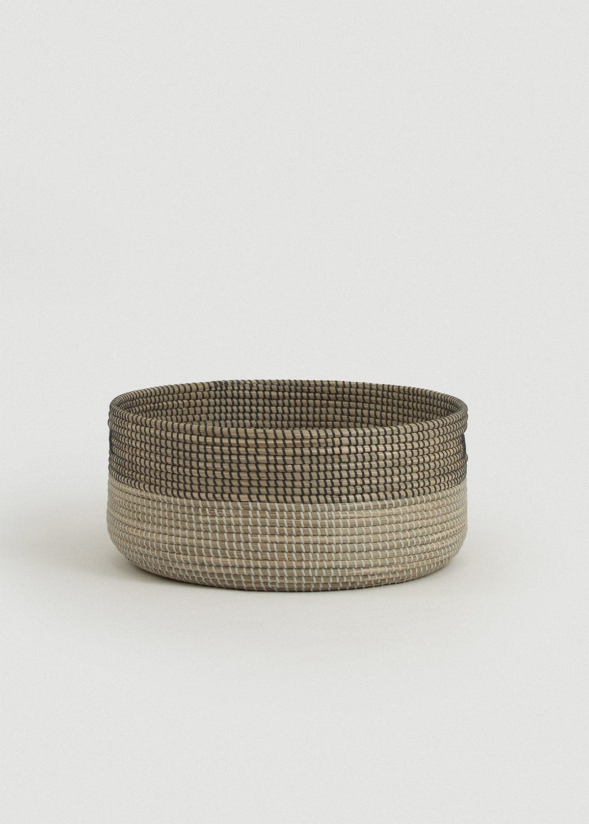 Side view of the Black Medina floor basket showing its wide, shallow shape and reinforced rim.