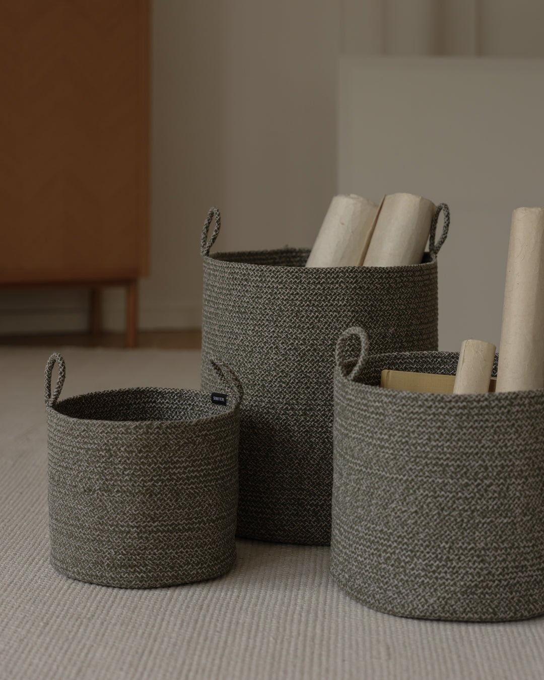 Three basket sizes used together to organize rolled materials in a neutral interior.