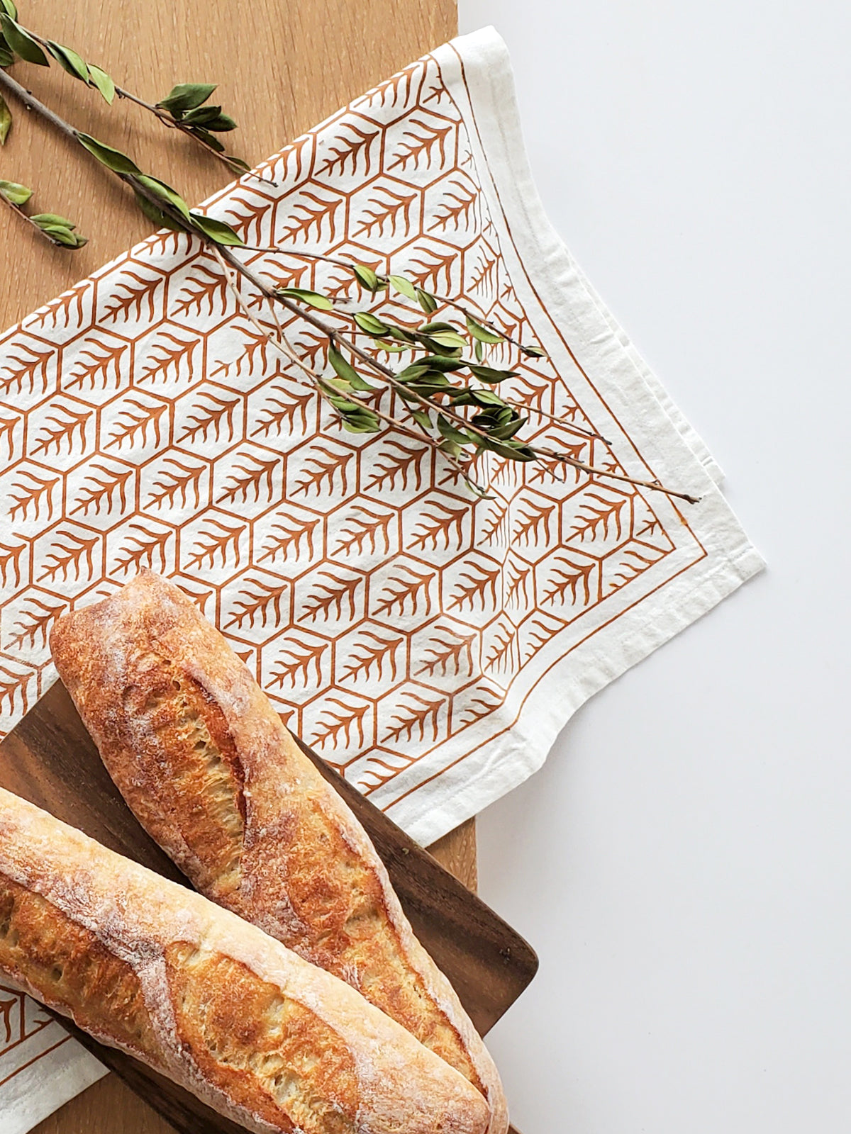 Korissa Hand Screen Printed Tea Towel, light brown print, on wood surface with baguettes