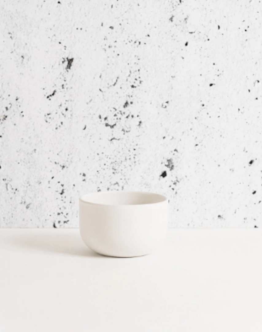 Stoneware bowl in Matte White against textured concrete background