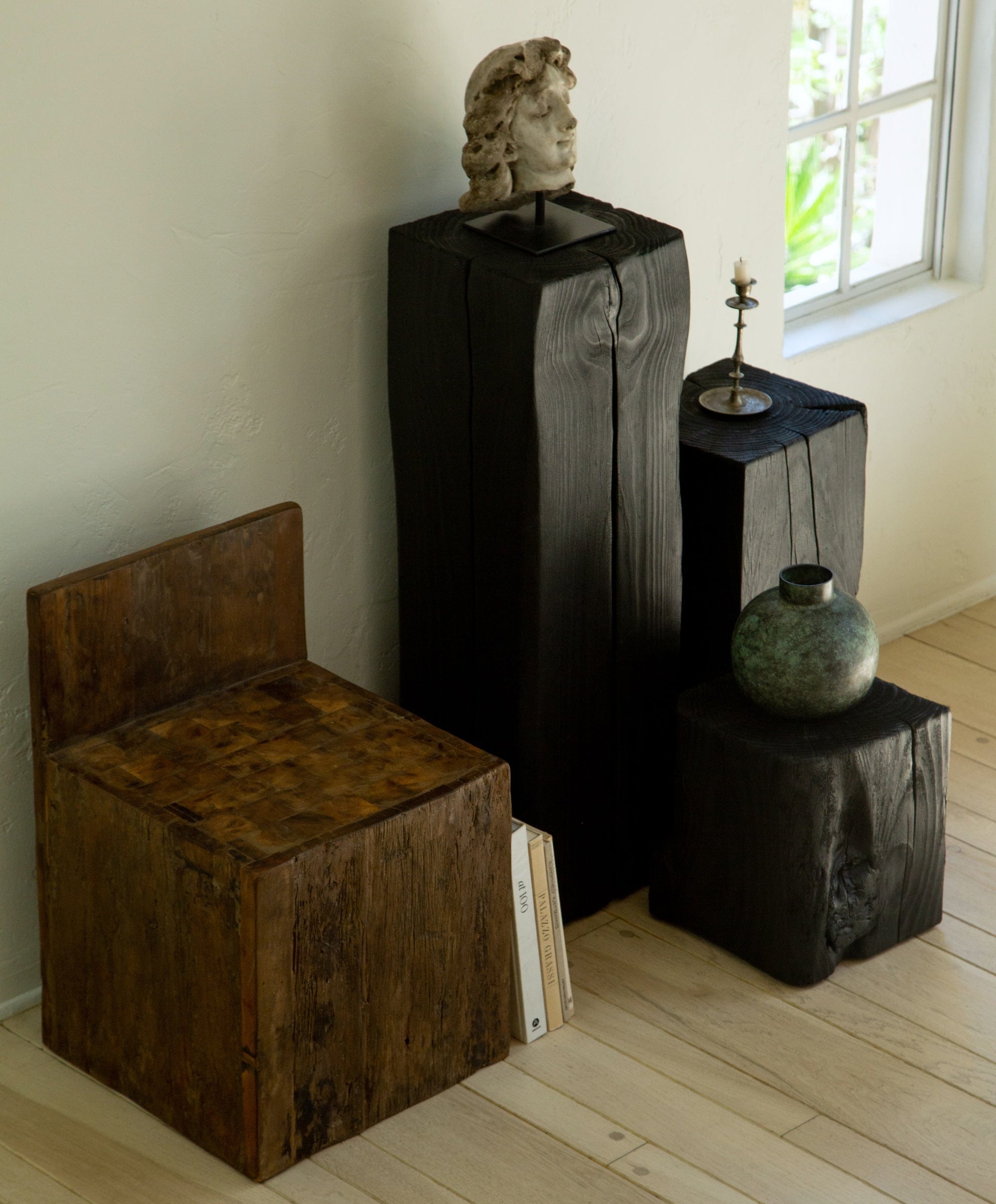 Charcoal sculpture pedestal styled with sculptural objects in interior setting