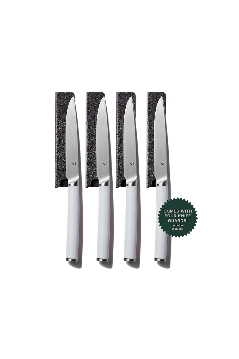 Set of four knives with knife guards on a green background