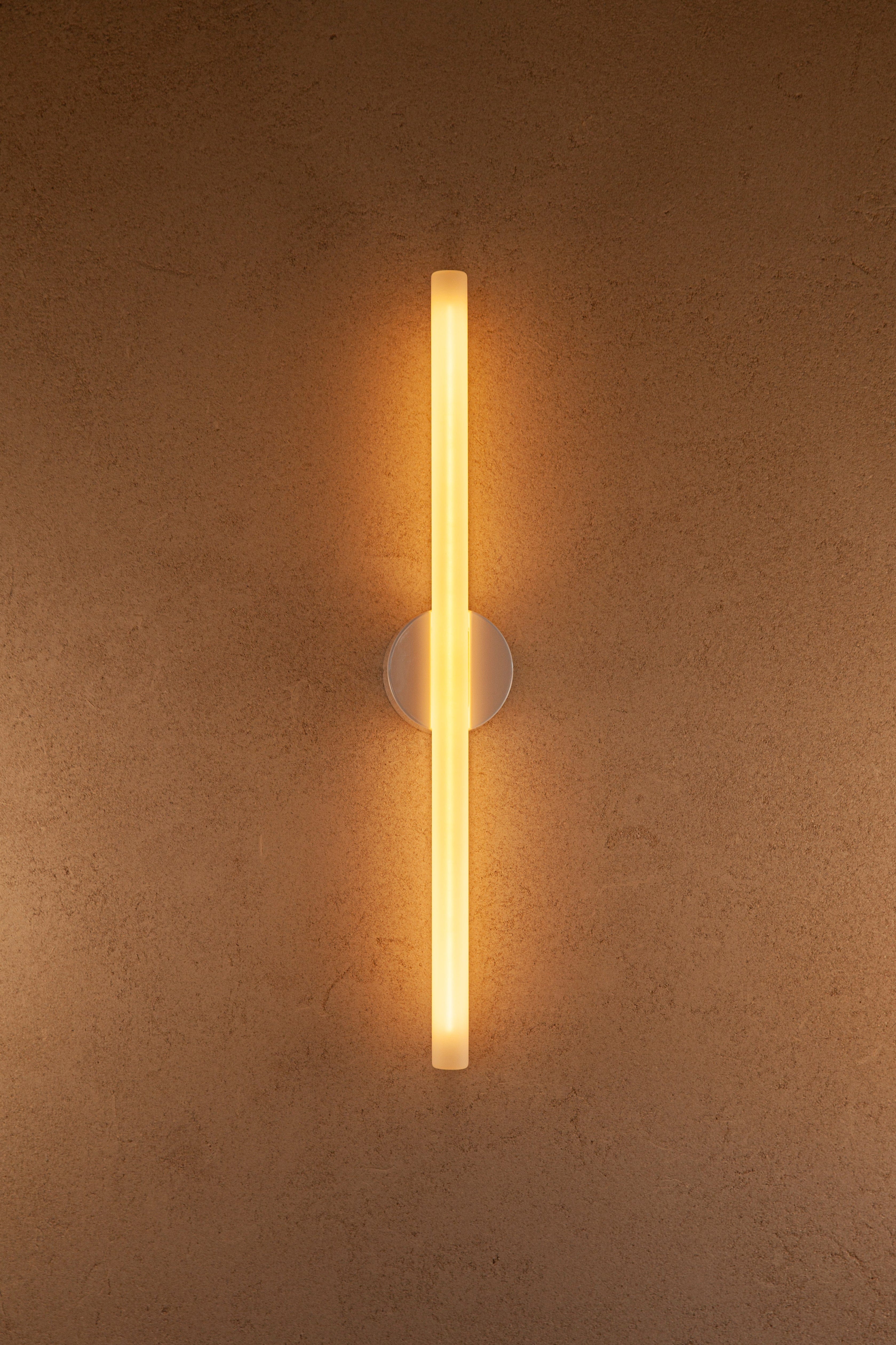 Wall-mounted light fixture casting a warm glow on a textured wall.