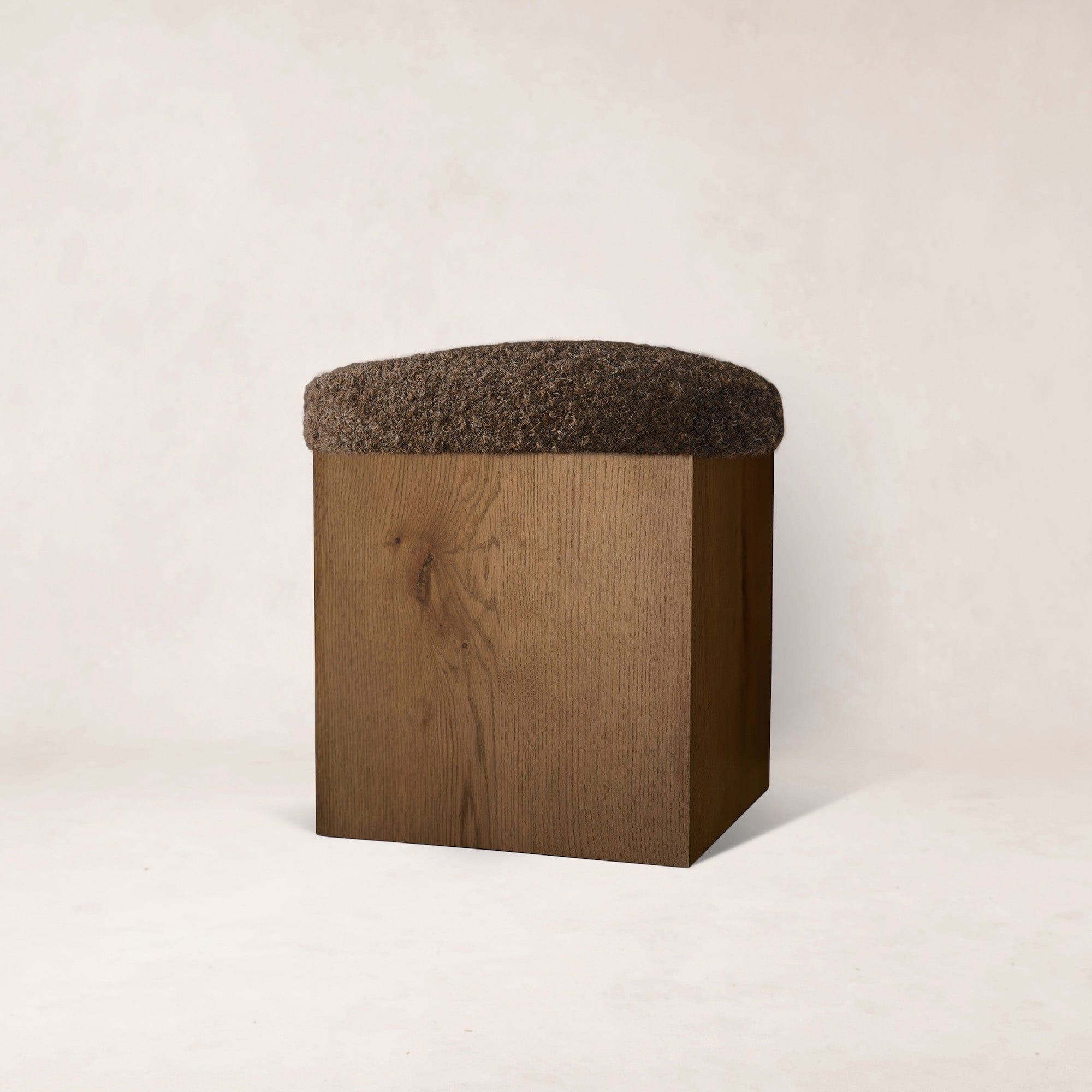 Wooden ottoman with a brown cushion on a white background
