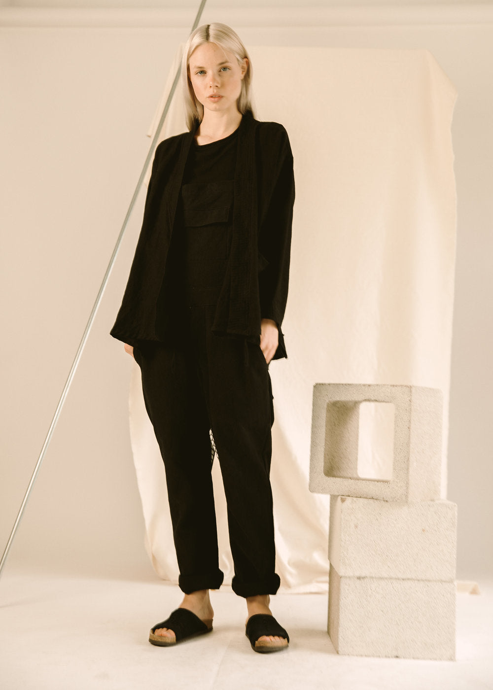 Model wearing a black GI jacket with matching black pants and sandals.