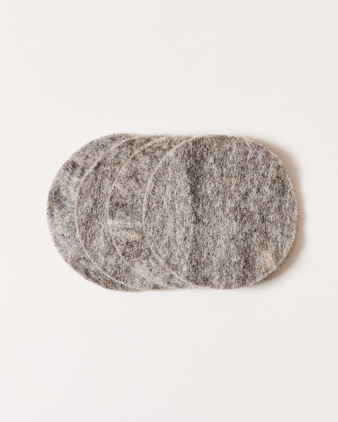 Stack of round heather-gray felt coasters, slightly fanned to show their thick, soft edges and natural fiber texture.