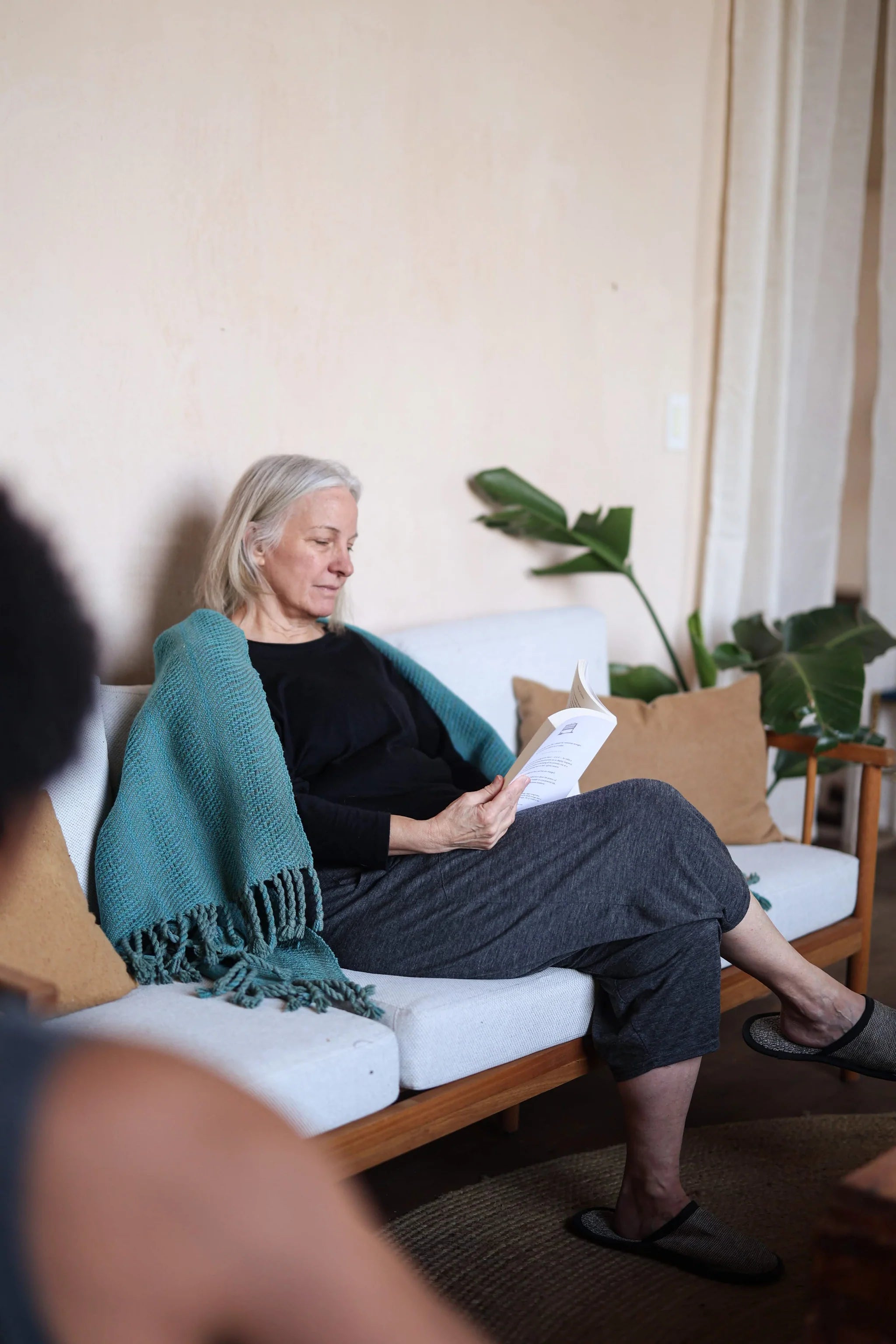 Woman wearing a merino wool lounge top while relaxing indoors, combining warmth, breathability, and everyday comfort.