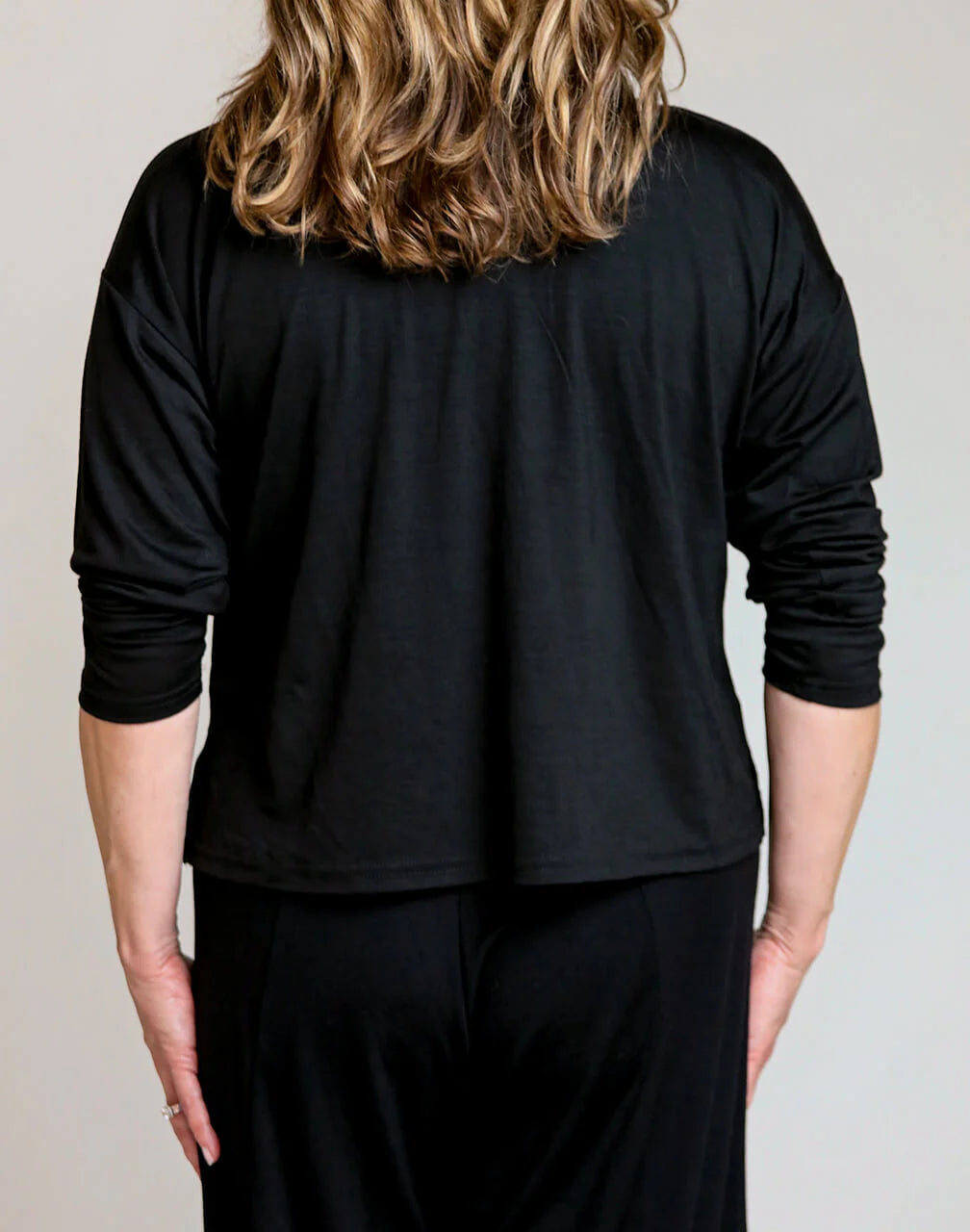 Back detail of a black merino wool lounge top featuring a relaxed fit and breathable natural wool construction.