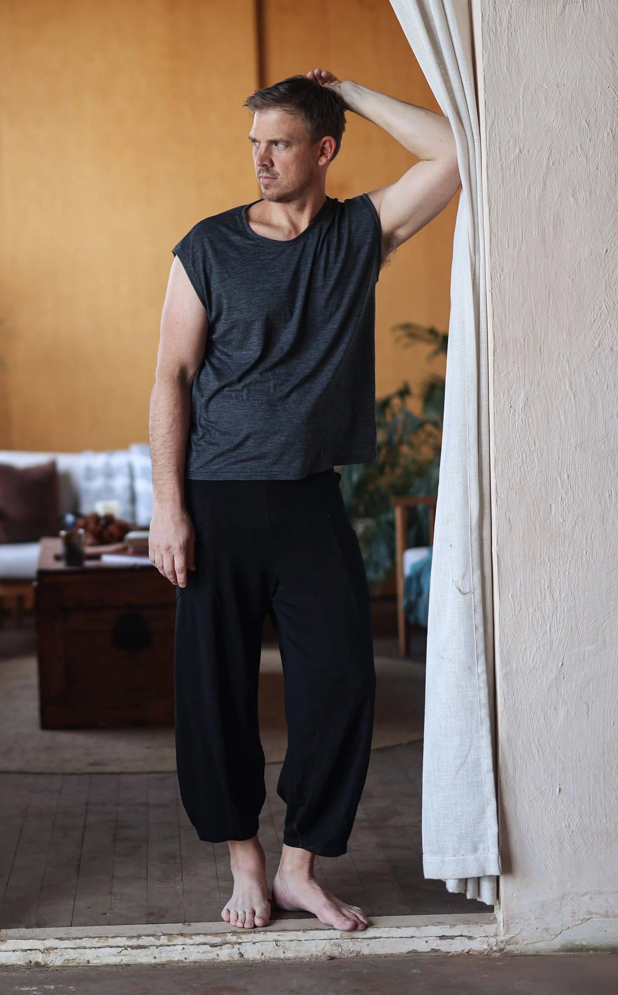 Man wearing black merino wool lounge pants and a matching merino tee, designed for post-sauna recovery, travel, and everyday comfort.