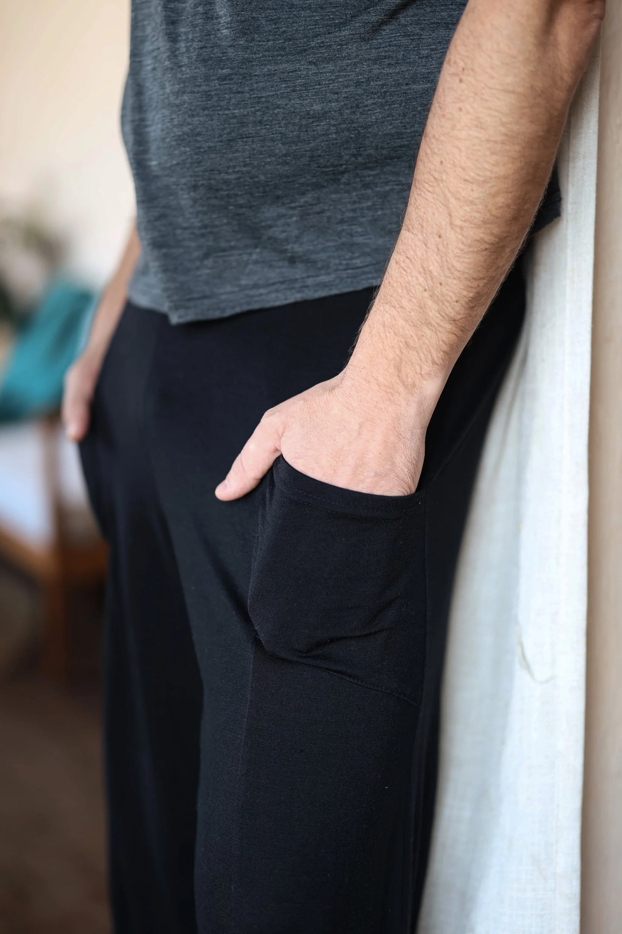 Close-up of black merino wool lounge pants highlighting functional pockets and soft natural wool fabric.