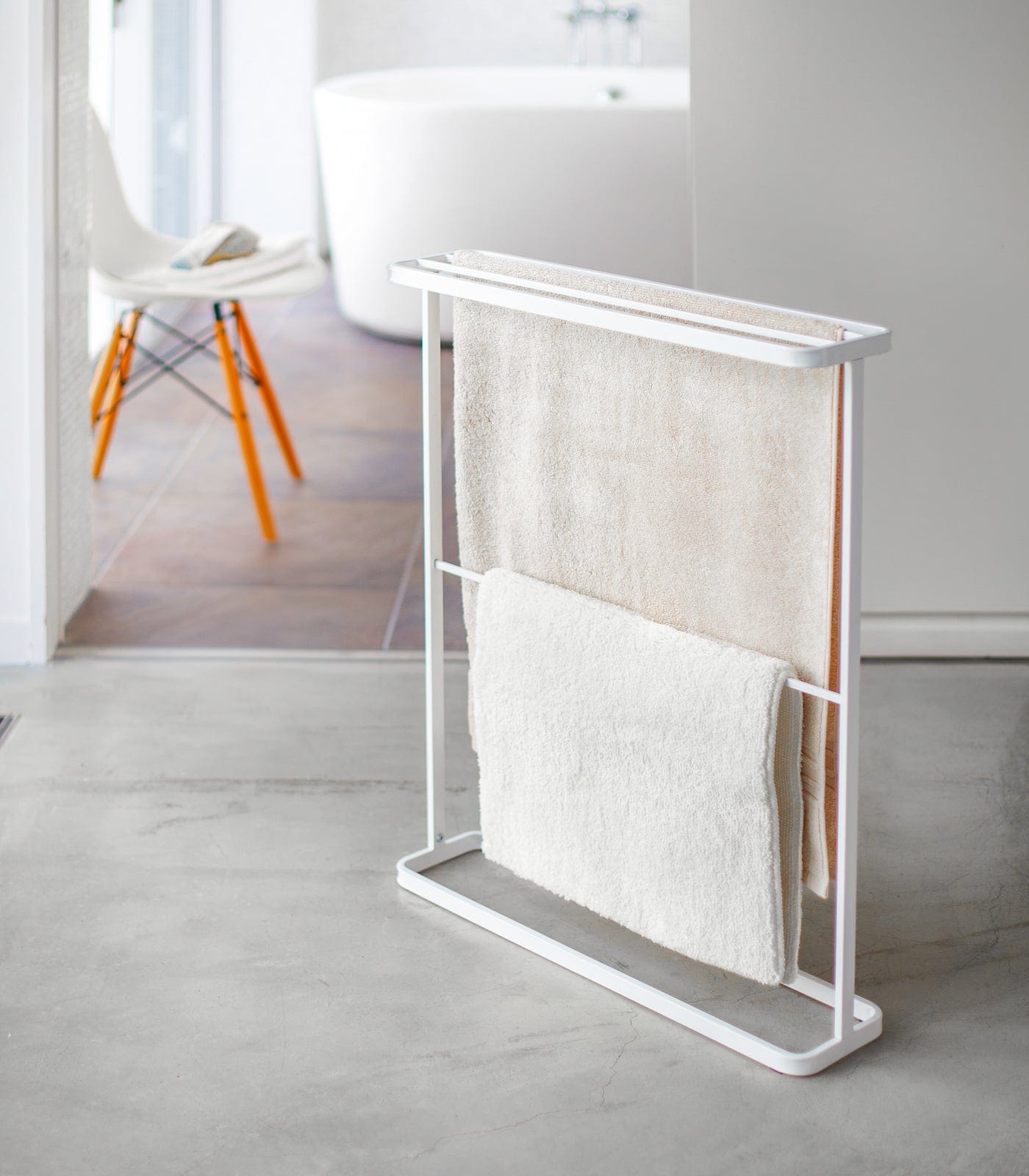 White towel rack with folded towels in a minimalistic bathroom setting. Bath Towel Hanger (30" H) - Steel