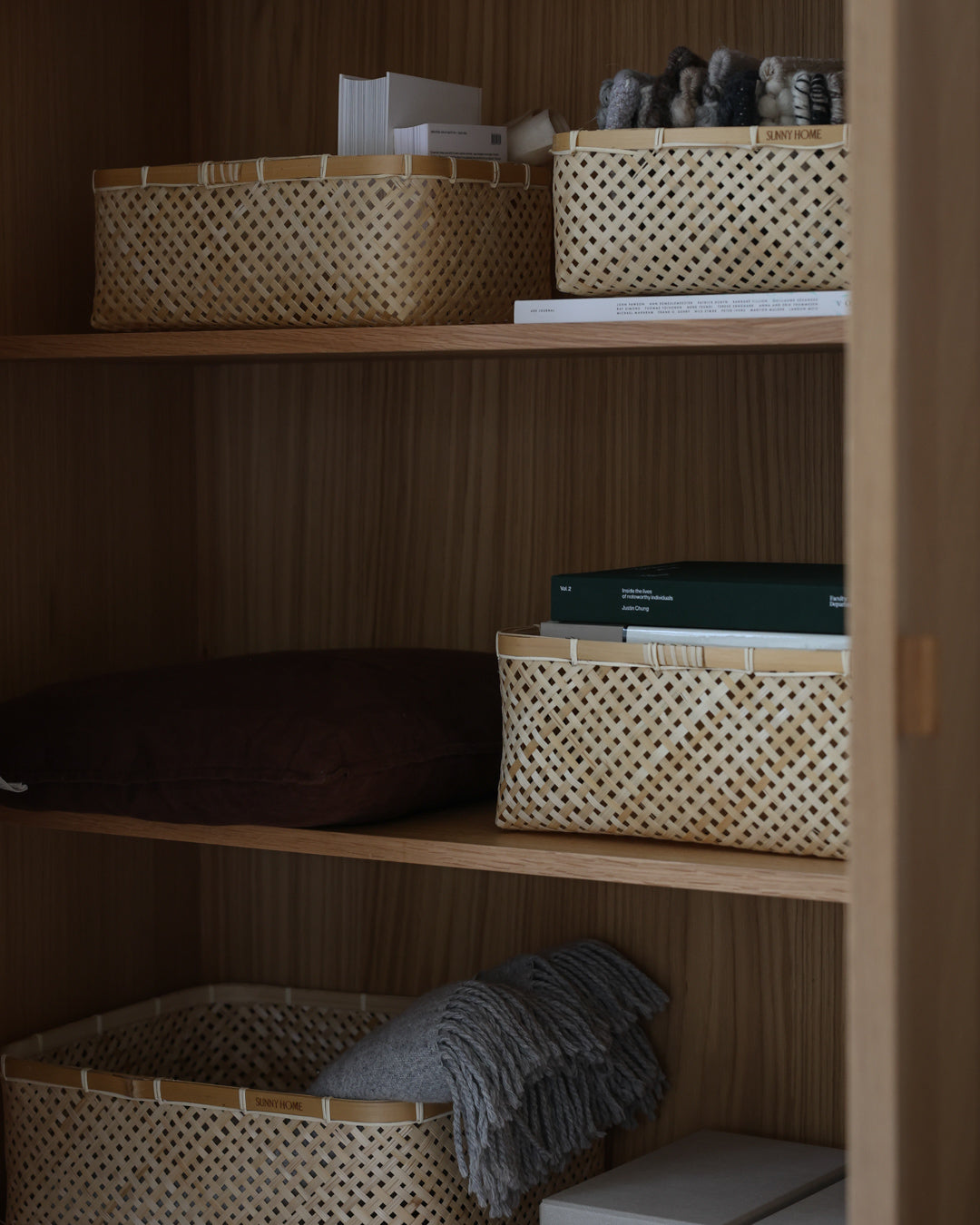 Closer view of rectangular bamboo baskets arranged across wooden shelves.