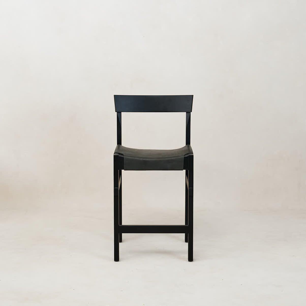 A black Shinto counter stool with a leather seat and wooden frame, displayed against a neutral background.