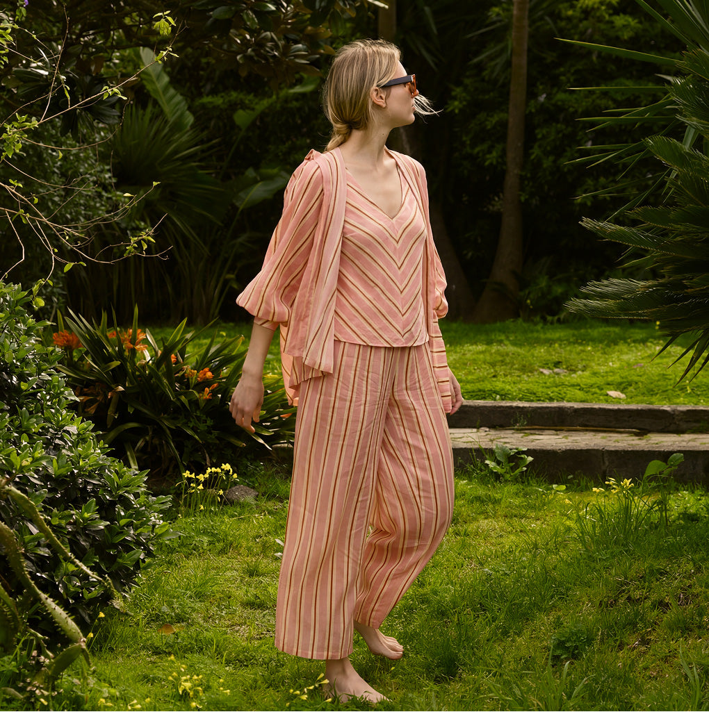 Model walking through a garden in the striped pajama set, with a matching shirt worn open over the sleeveless top.