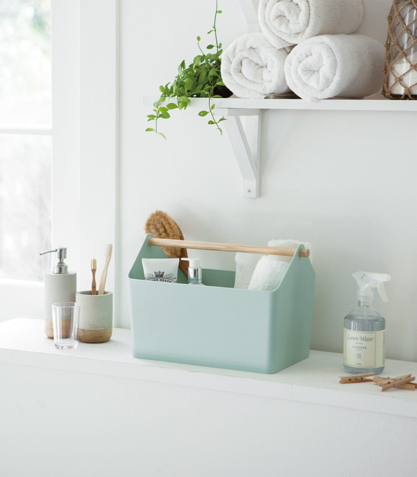 Mint green caddy with cleaning supplies on a white surface