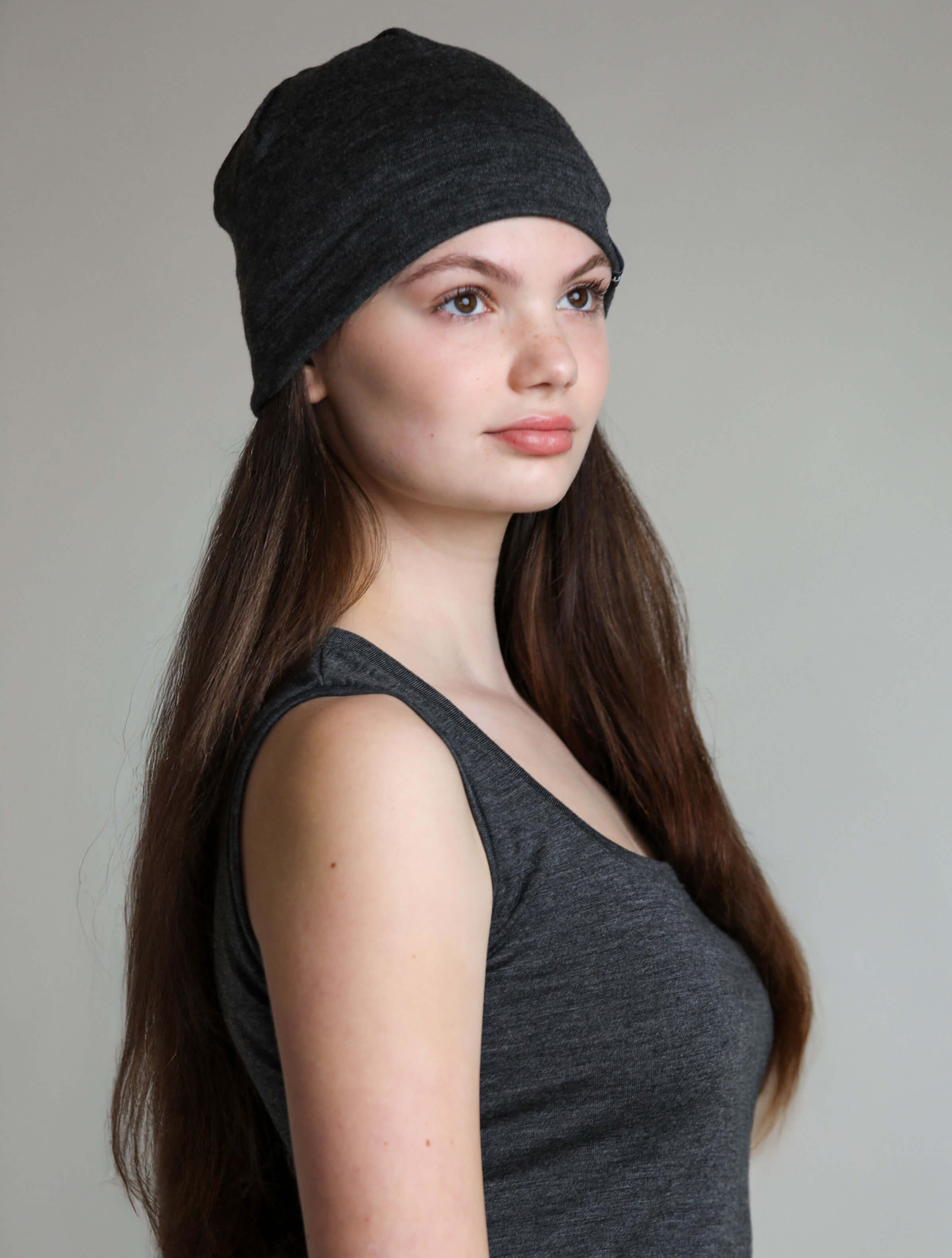 Woman wearing a charcoal merino wool sauna beanie designed to protect hair and scalp during sauna and wellness rituals.