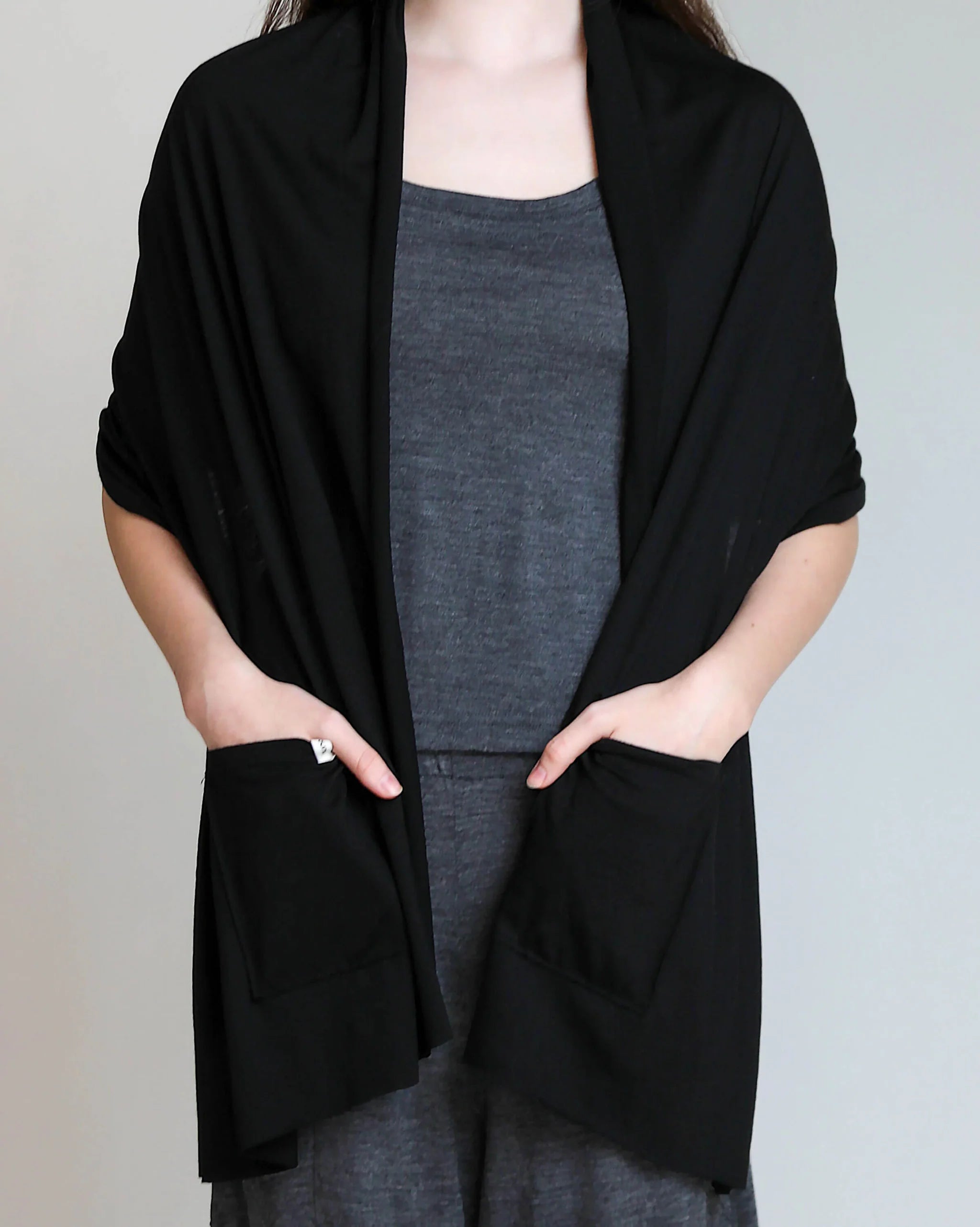 Black merino wool pocket wrap styled as an elegant layering piece for travel, recovery, and everyday wear.
