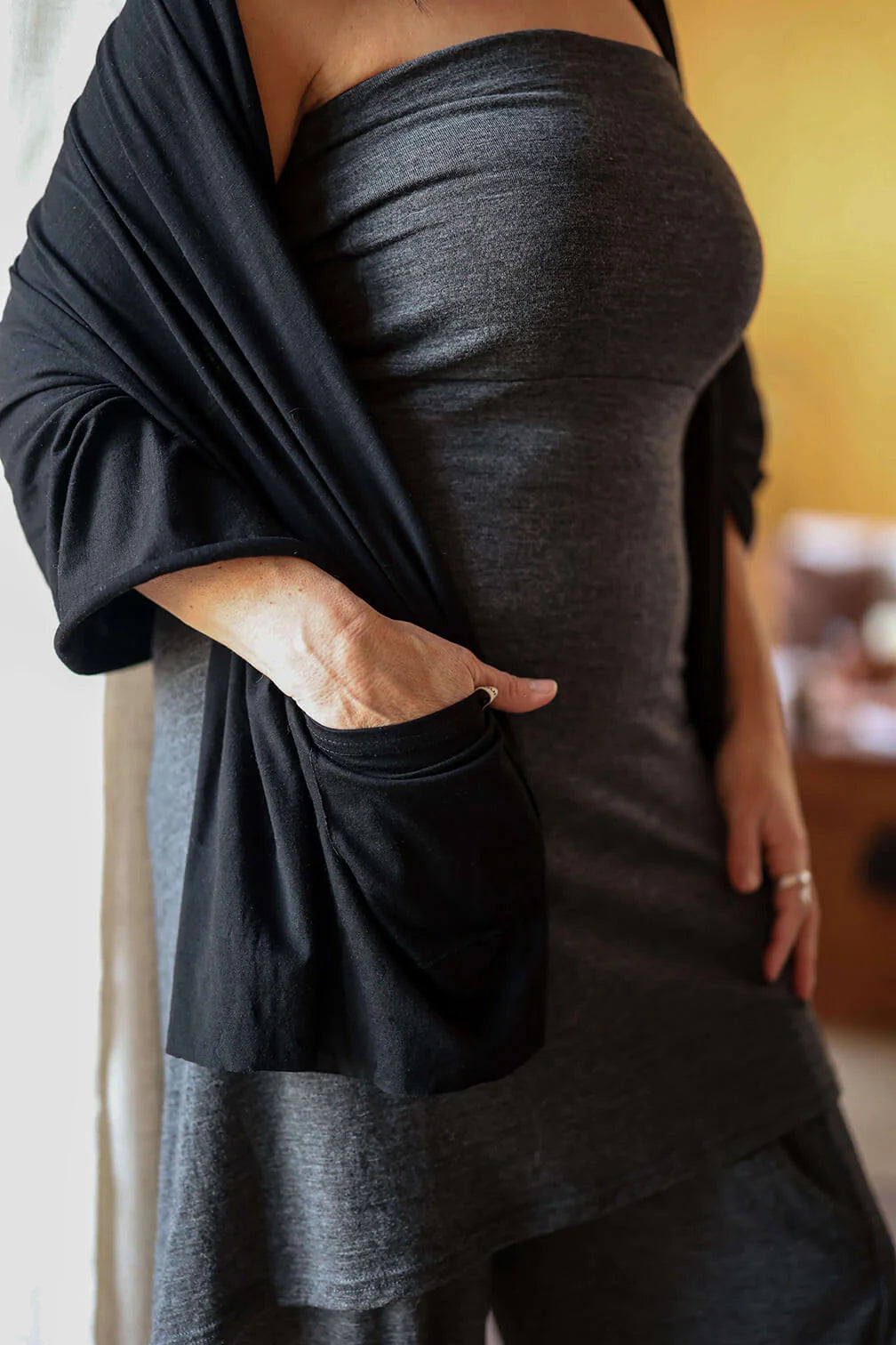 Woman wearing a charcoal merino wool pocket wrap with practical pockets designed for everyday comfort and wellness rituals.
