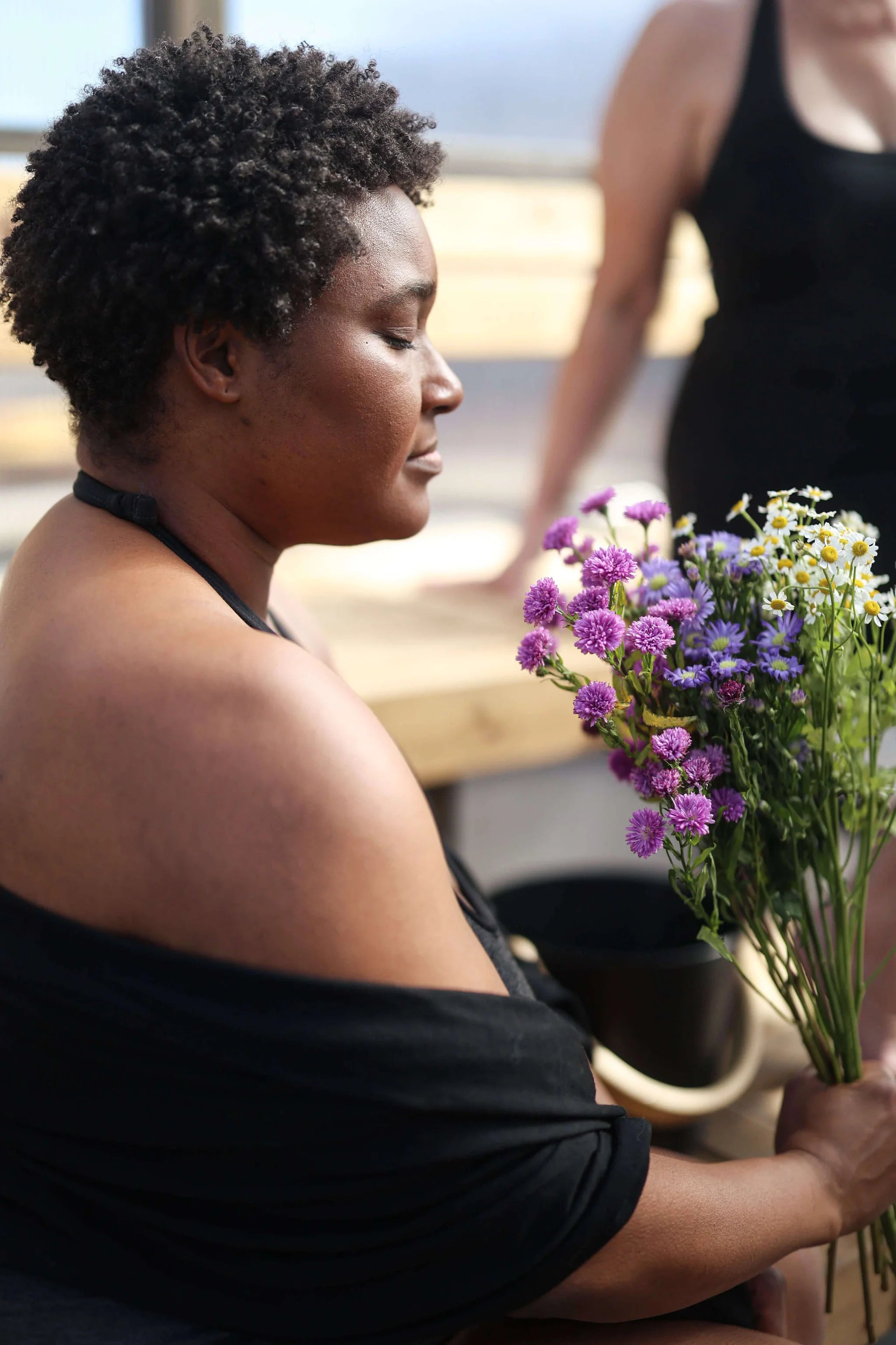 Woman wrapped in a black merino wool pocket wrap during a quiet wellness ritual, emphasizing comfort and warmth.