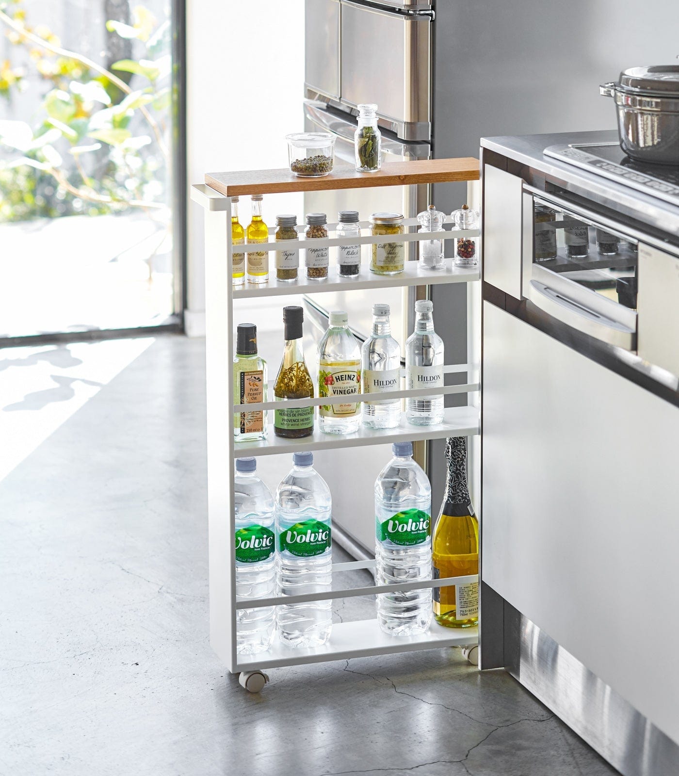 Kitchen island cart with various bottles in a modern kitchen setting. Slim Storage Cart (32" H) - Steel