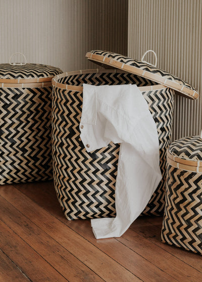 Java baskets used as laundry hampers, with white fabric draped from an open basket.