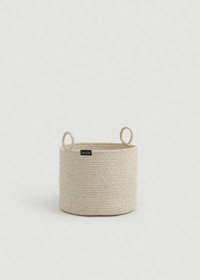Beige melange cotton rope storage basket with a cylindrical shape and two upright loop handles.