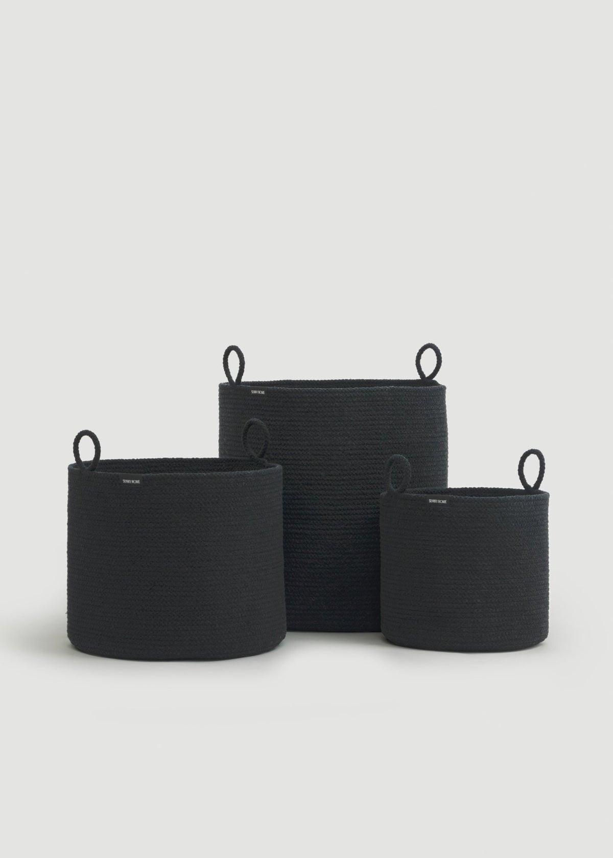 Three black cotton rope baskets in graduated sizes arranged together.