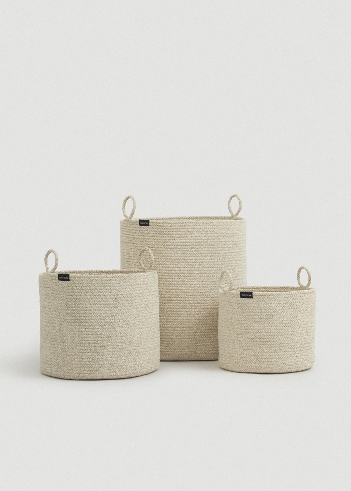 Three beige cotton rope baskets in graduated sizes arranged together.