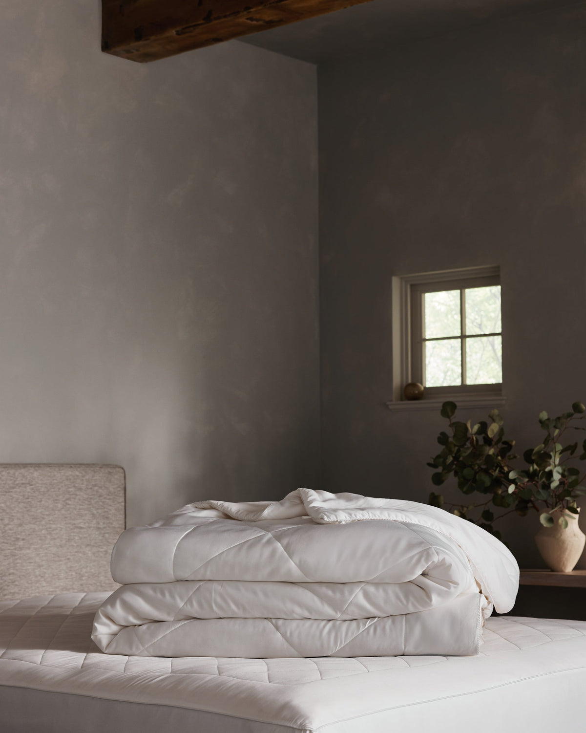 White Bamboo Viscose Comforter folded on a pale background, with one corner turned back to show its quilted surface, softly padded layers, and finished edge.