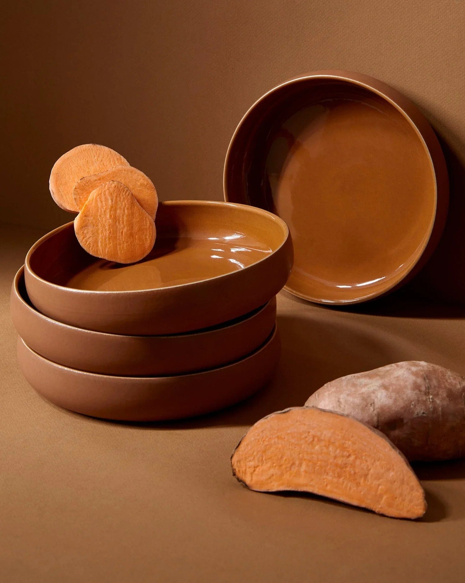 Stoneware bowls in Terracotta stacked with sweet potato on warm-toned background