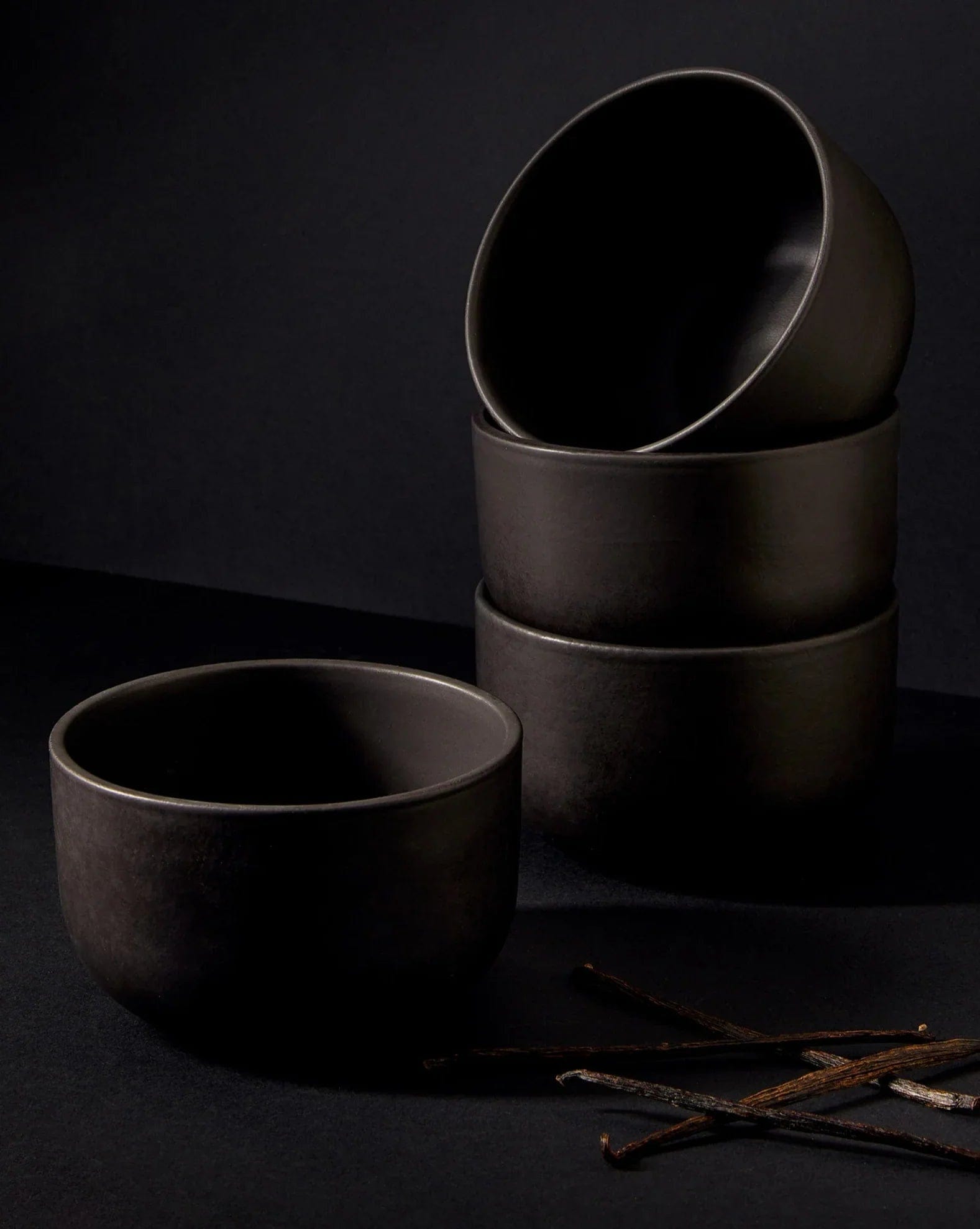 Stoneware bowls in Matte Black stacked with vanilla pods on dark background