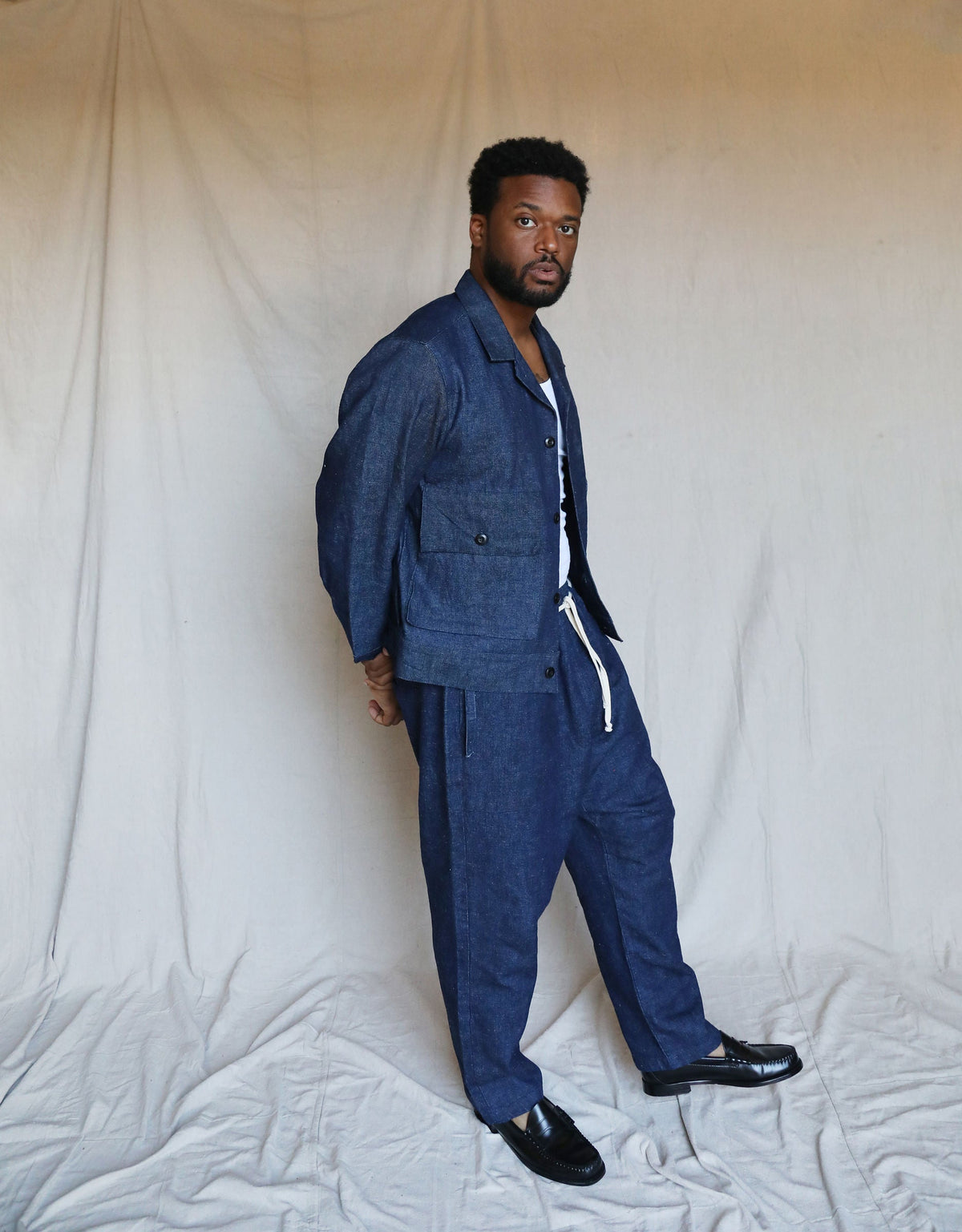 Full-length studio portrait of a model wearing the indigo Studio Coat with matching drawstring pants.