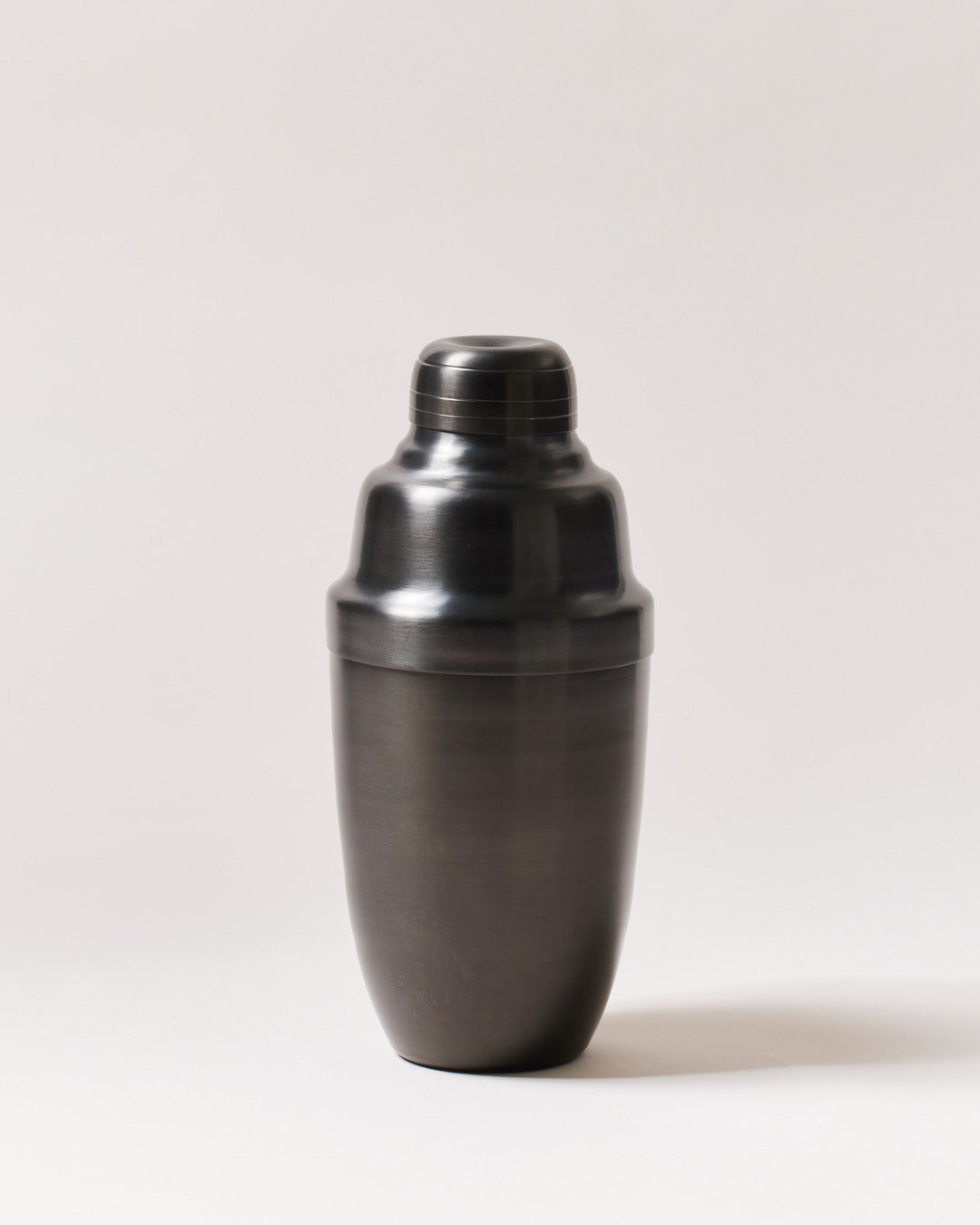Brushed-onyx cocktail shaker displayed upright, showing its rounded body, fitted lid, and removable cap.