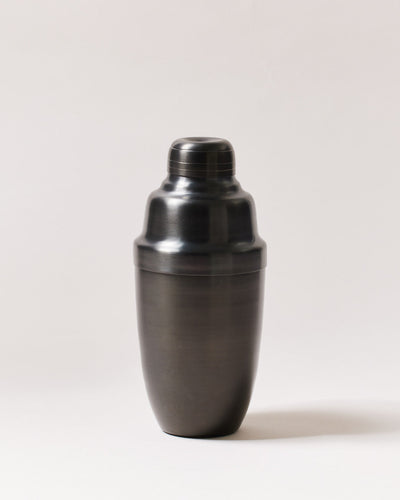 Brushed-onyx cocktail shaker displayed upright, showing its rounded body, fitted lid, and removable cap.
