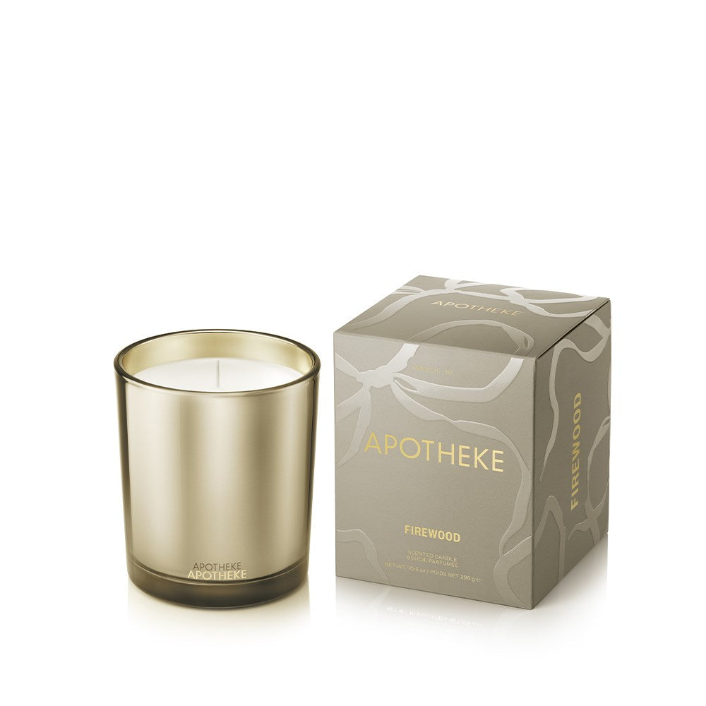 Firewood Classic Candle in a smoky olive-gray glass vessel beside a matching marbled box with gold APOTHEKE lettering.