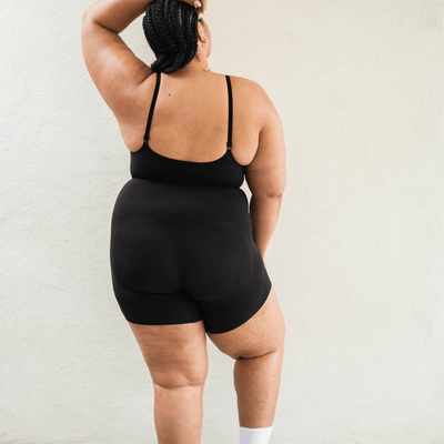 Back view of black shapewear bodysuit on plus size model with sculpting support