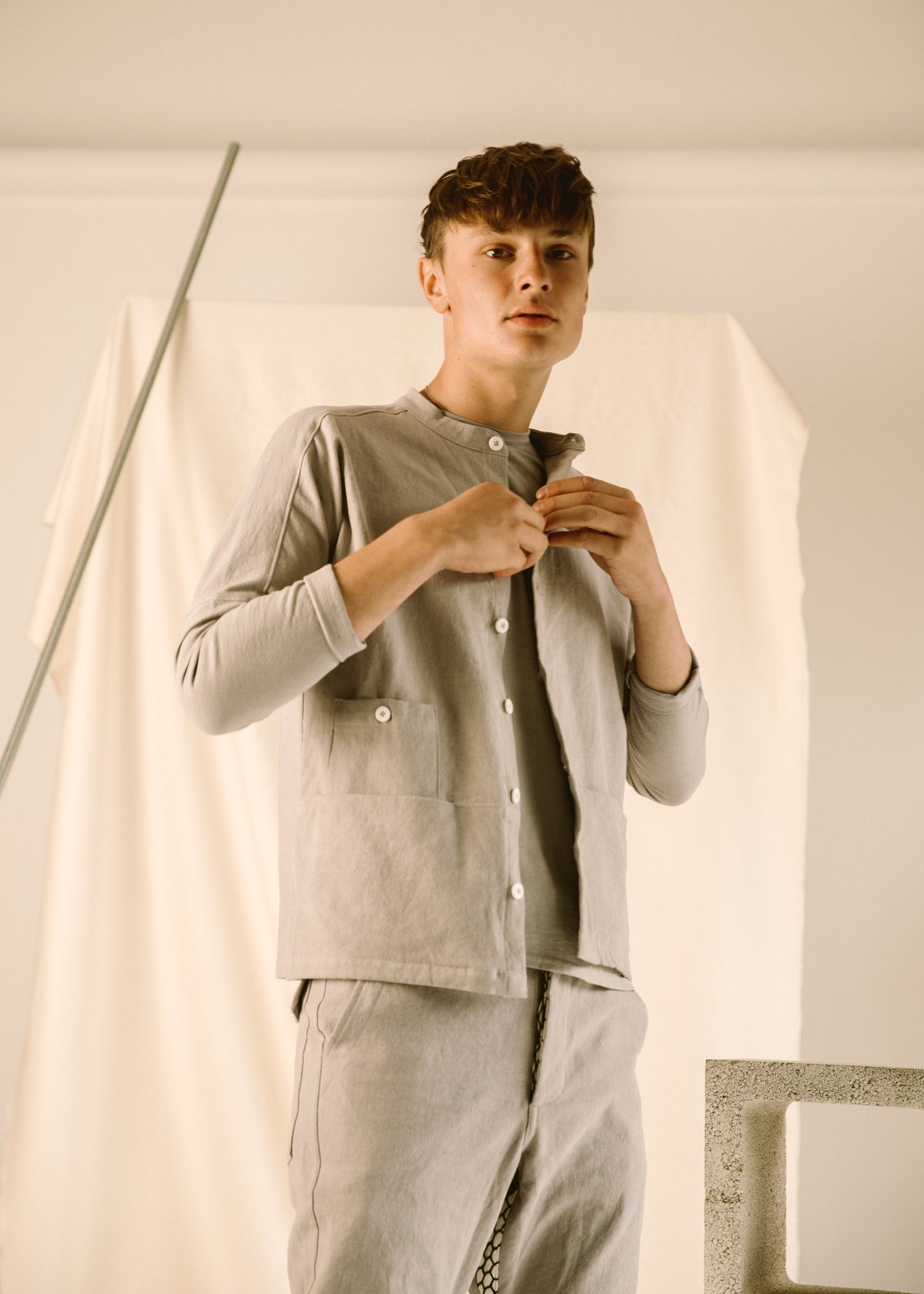 Model fastening a light gray collarless Raj corduroy coat over matching pants.