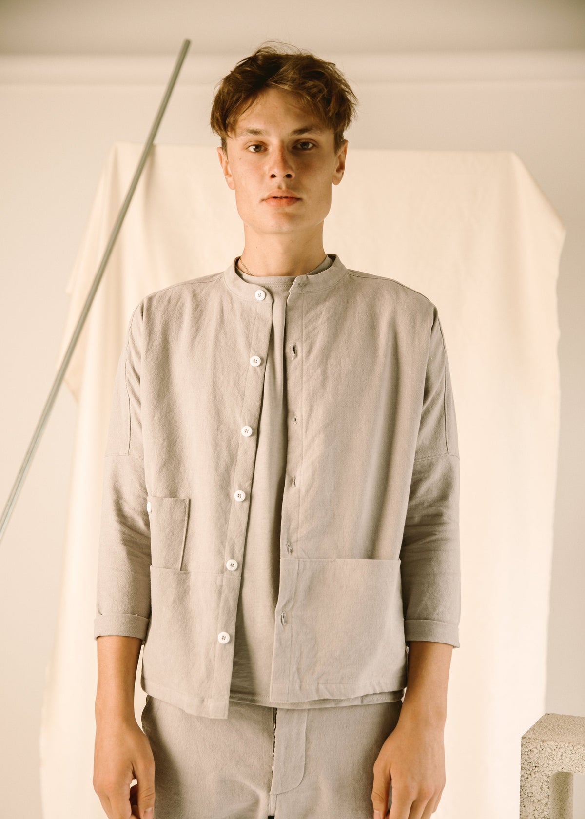Front view of a model wearing the buttoned light gray corduroy coat.