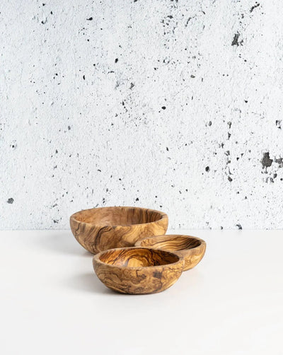 Olive wood nesting bowls set of 3 against textured concrete wall background